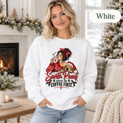 White crewneck sweatshirt featuring a festive “Santa Paws Bring Me Coffee First” design with a woman holding a mug beside a dog in a Santa hat, shown on a female model in a cozy Christmas setting.