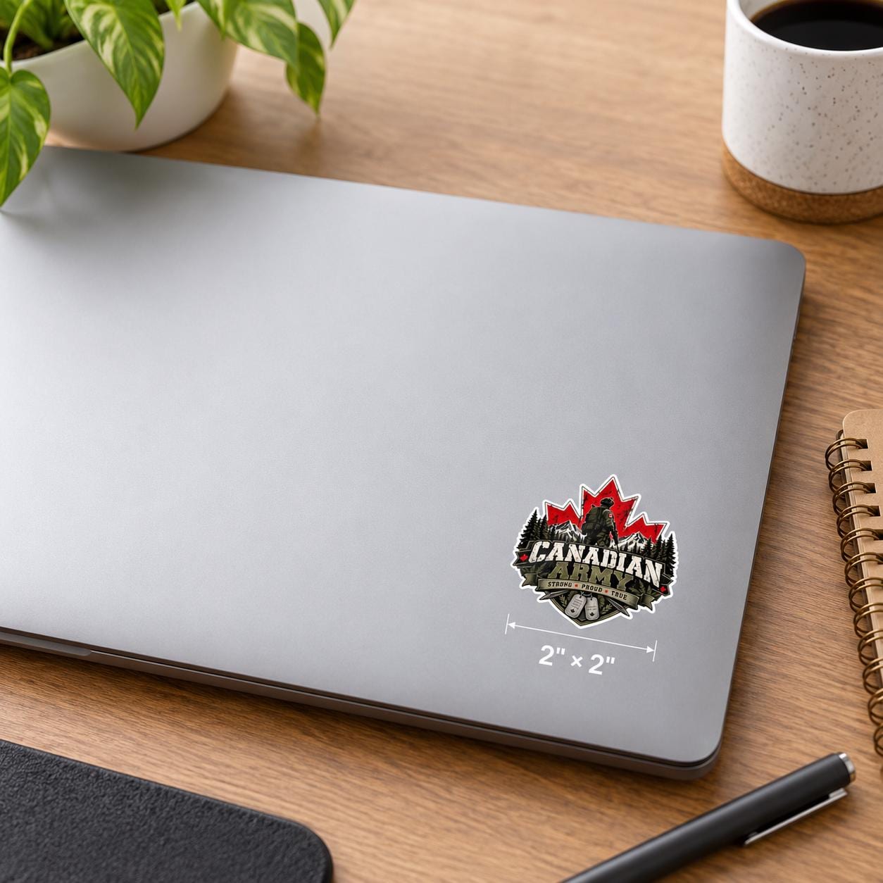 2x2 inch Canadian Army UV DTF sticker mockup on a silver laptop featuring a red maple leaf, soldier silhouette, mountains, pine trees, and “Strong Proud True” text.