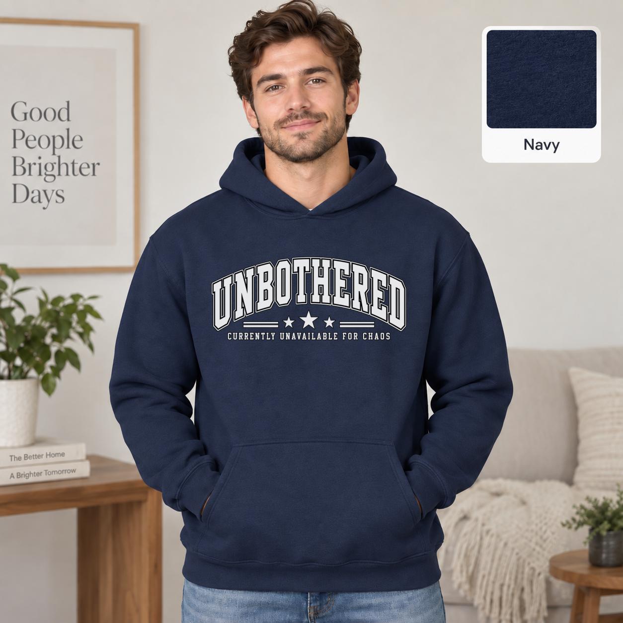 Male model wearing a navy Gildan 18500 hoodie with a clean white Unbothered graphic and the phrase Currently Unavailable for Chaos, styled for a minimalist neutral aesthetic.