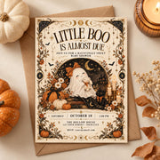 Little Boo Is Almost Due editable Halloween baby shower invitation displayed on a simple autumn flatlay with pumpkins and candle.
