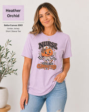 Woman wearing an Heather Orchid Bella+Canvas 3001 unisex t-shirt featuring a cute pumpkin nurse graphic and the phrase “Nurse Cute But Clinically Tired.”