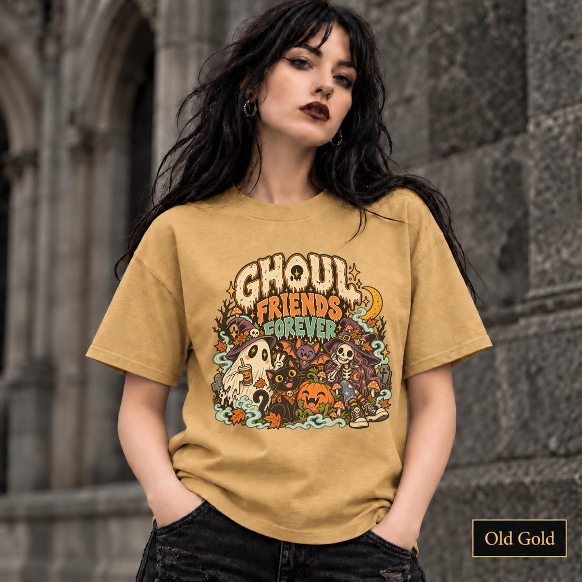 Old Gold unisex T-shirt featuring a colorful “Ghoul Friends Forever” Halloween graphic with a ghost, black cat, pumpkin, witchy skeleton, bats, mushrooms, crescent moon, and autumn accents.