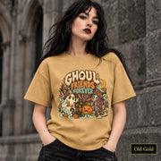 Old Gold unisex T-shirt featuring a colorful “Ghoul Friends Forever” Halloween graphic with a ghost, black cat, pumpkin, witchy skeleton, bats, mushrooms, crescent moon, and autumn accents.