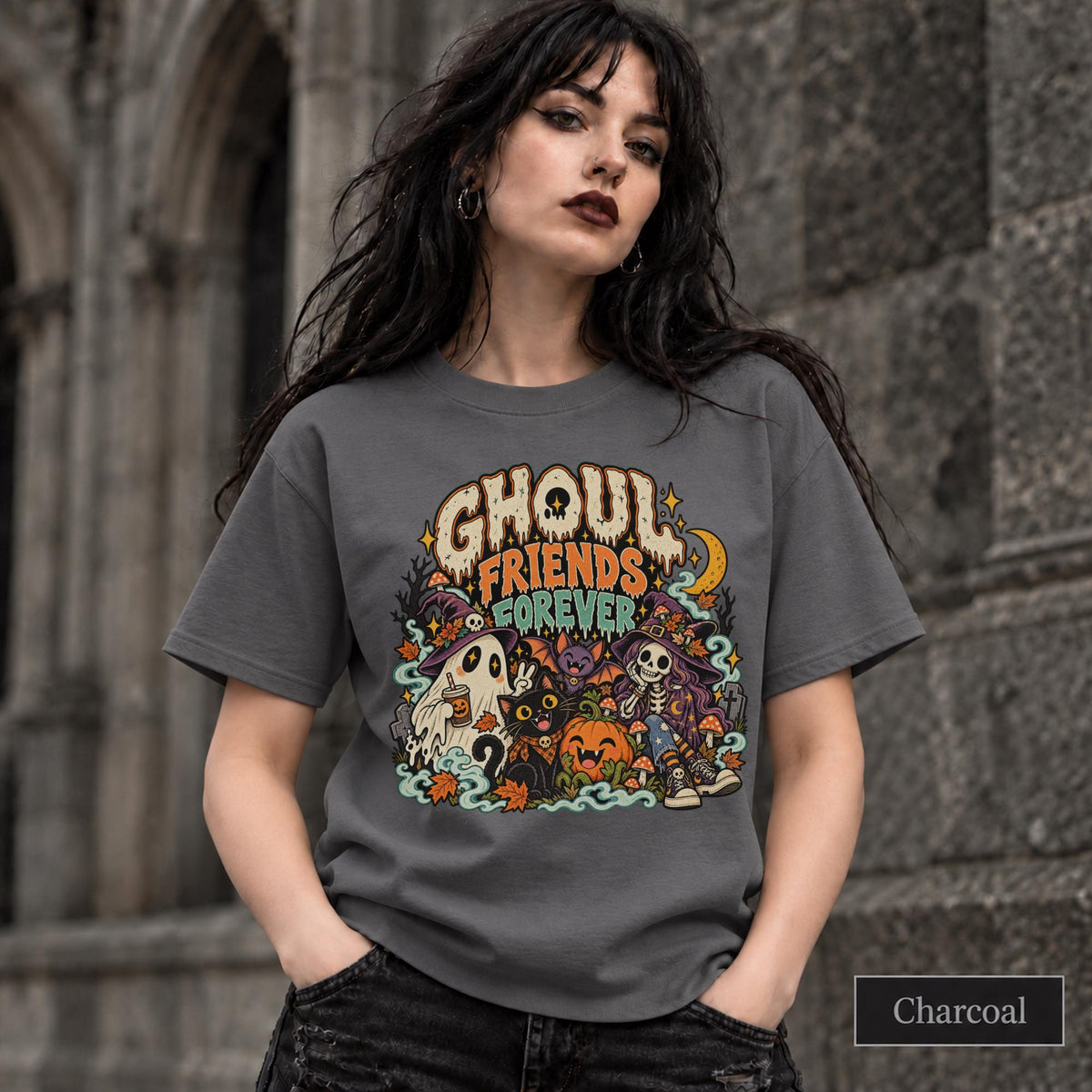 Charcoal unisex T-shirt featuring a colorful “Ghoul Friends Forever” Halloween graphic with a ghost, black cat, pumpkin, witchy skeleton, bats, mushrooms, crescent moon, and autumn accents.