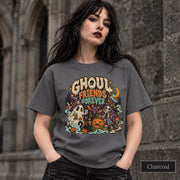 Charcoal unisex T-shirt featuring a colorful “Ghoul Friends Forever” Halloween graphic with a ghost, black cat, pumpkin, witchy skeleton, bats, mushrooms, crescent moon, and autumn accents.