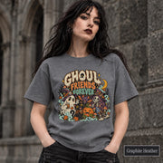 Graphite Heather unisex T-shirt featuring a colorful “Ghoul Friends Forever” Halloween graphic with a ghost, black cat, pumpkin, witchy skeleton, bats, mushrooms, crescent moon, and autumn accents.