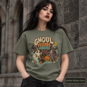 Heather Military Green unisex T-shirt featuring a colorful “Ghoul Friends Forever” Halloween graphic with a ghost, black cat, pumpkin, witchy skeleton, bats, mushrooms, crescent moon, and autumn accents.