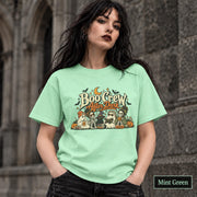 Mint Green unisex T-shirt featuring a “Boo Crew After Dark” Halloween design with ghosts, skeletons, pumpkins, books, bats, drinks, and a crescent moon in retro orange and cream tones.
