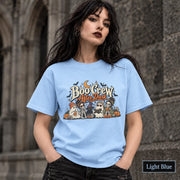 Light Blue unisex T-shirt featuring a “Boo Crew After Dark” Halloween design with ghosts, skeletons, pumpkins, books, bats, drinks, and a crescent moon in retro orange and cream tones.