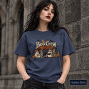 Heather Navy unisex T-shirt featuring a “Boo Crew After Dark” Halloween design with ghosts, skeletons, pumpkins, books, bats, drinks, and a crescent moon in retro orange and cream tones.