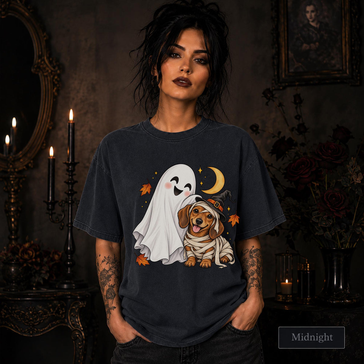 Midnight unisex T-shirt featuring a smiling white ghost beside a mummy-wrapped puppy wearing a witch hat, with a crescent moon, stars, and orange autumn leaves.