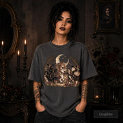 Graphite unisex T-shirt featuring a gothic fantasy scene with a unicorn, owls, raven, crescent moon, mushrooms, candles, flowers, and twisted woodland branches.