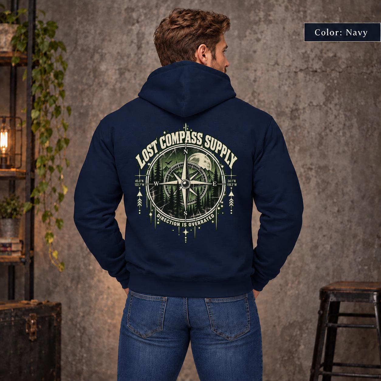 Navy unisex hoodie shown from the back with a large Lost Compass Supply graphic featuring a vintage compass, moonlit forest, directional markings, and the phrase “Direction Is Overrated.”