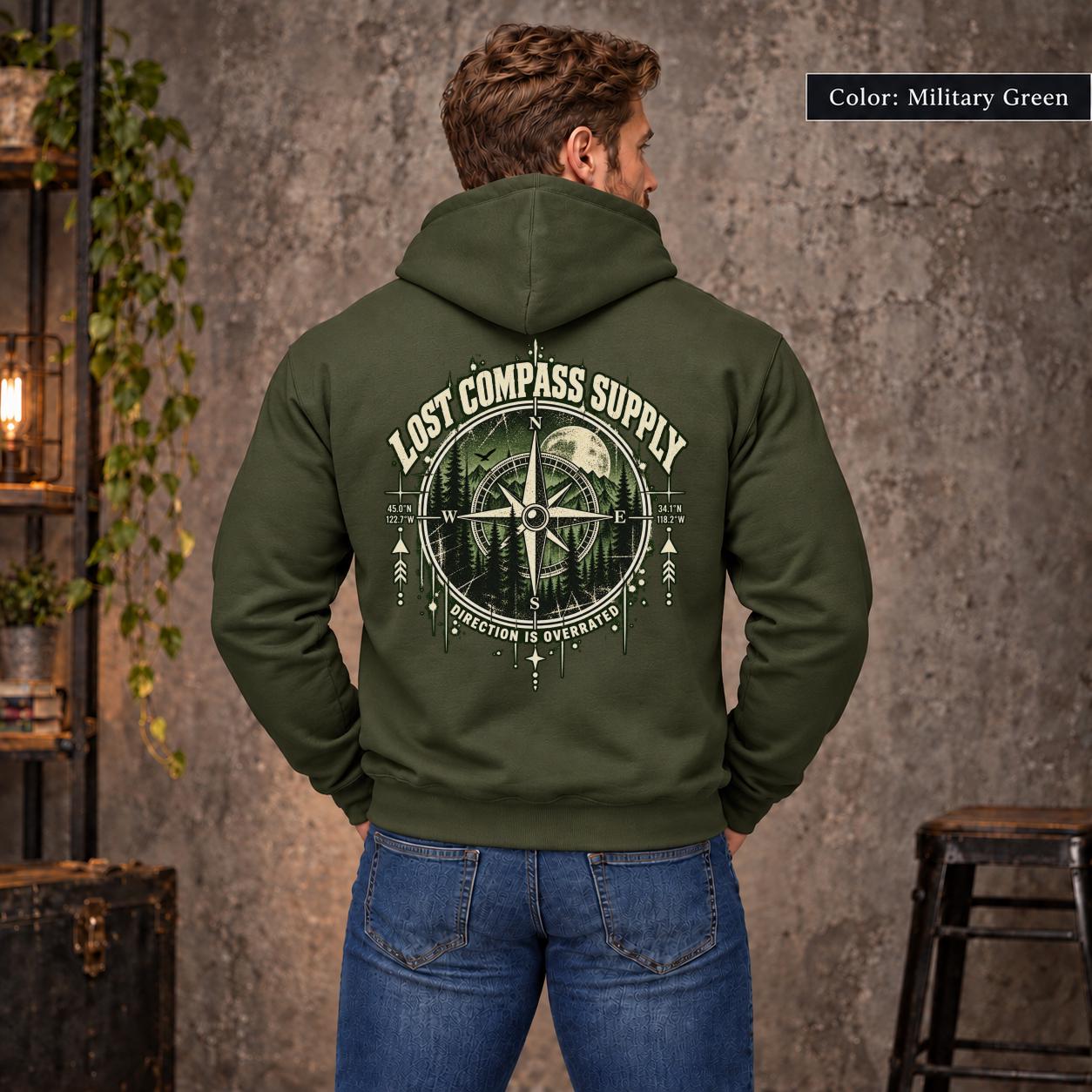 Military Green unisex hoodie shown from the back with a large Lost Compass Supply graphic featuring a vintage compass, moonlit forest, directional markings, and the phrase “Direction Is Overrated.”