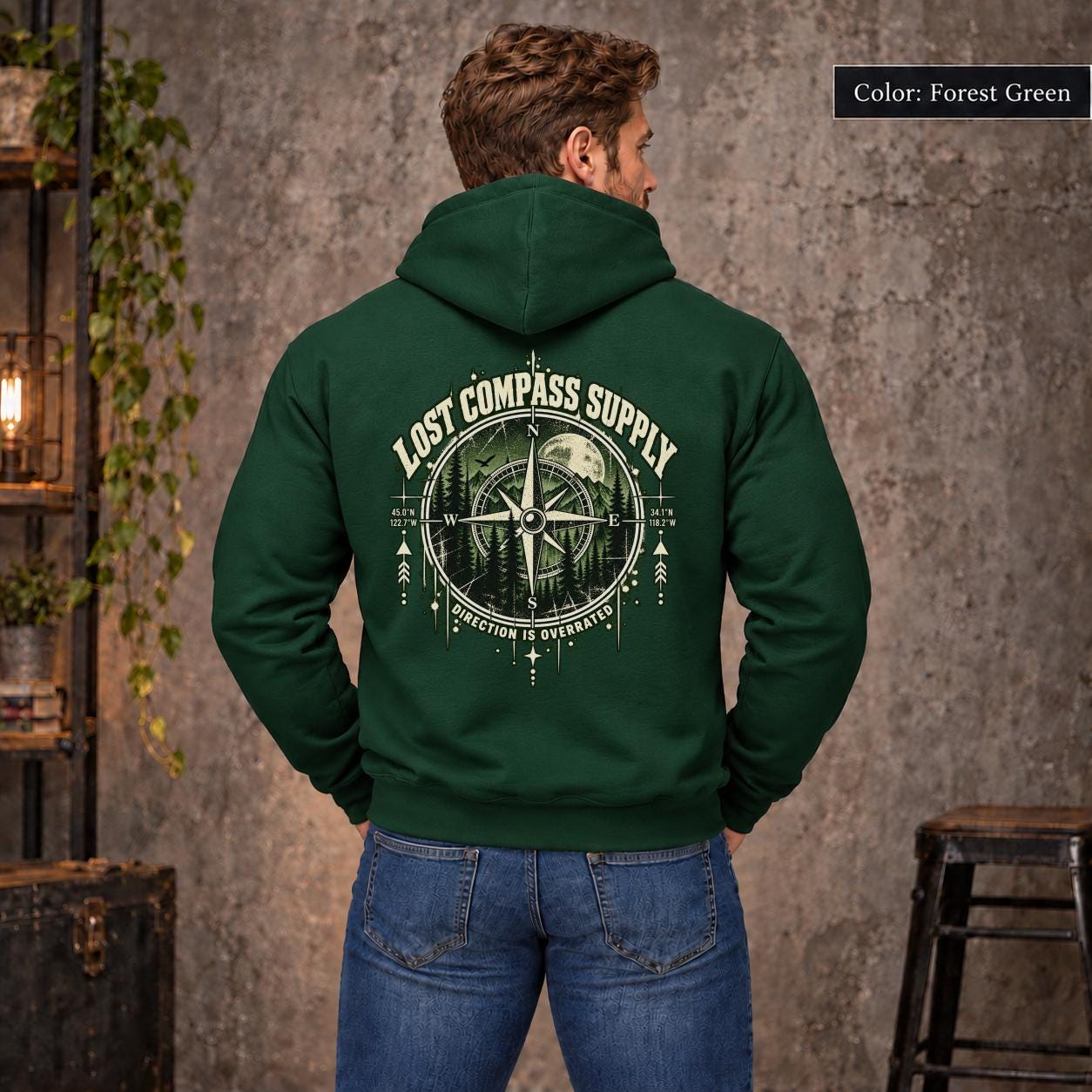 Forest Green unisex hoodie shown from the back with a large Lost Compass Supply graphic featuring a vintage compass, moonlit forest, directional markings, and the phrase “Direction Is Overrated.”