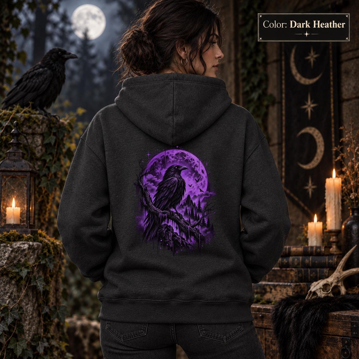 Dark heather unisex hoodie displayed from the back with a vivid purple raven and moon graphic, set against a gothic woodland scene with lanterns and dark forest styling.