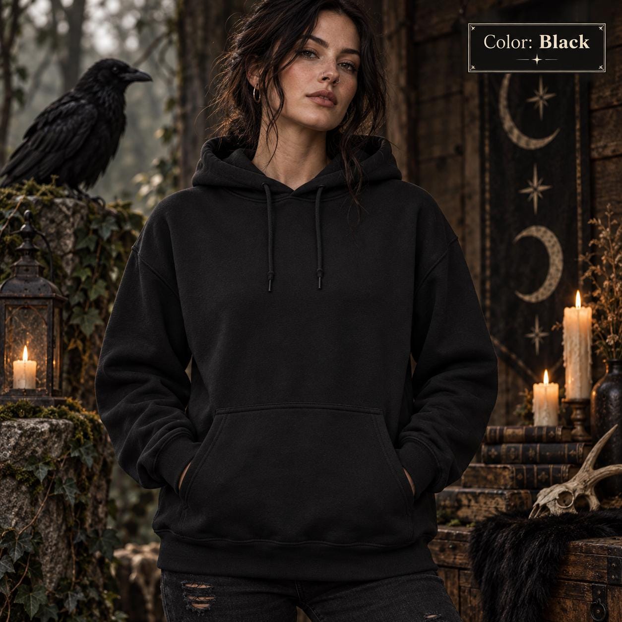 Black unisex hoodie shown from the front, featuring a large purple raven perched on the back against a glowing violet moon, surrounded by mountains, pine trees, mist, and celestial details.