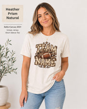 Heather Prism Natural Bella+Canvas 3001 unisex T-shirt featuring a customizable vintage football graphic with bold “Team Name” lettering, leopard-print bow, stars, and distressed varsity details.