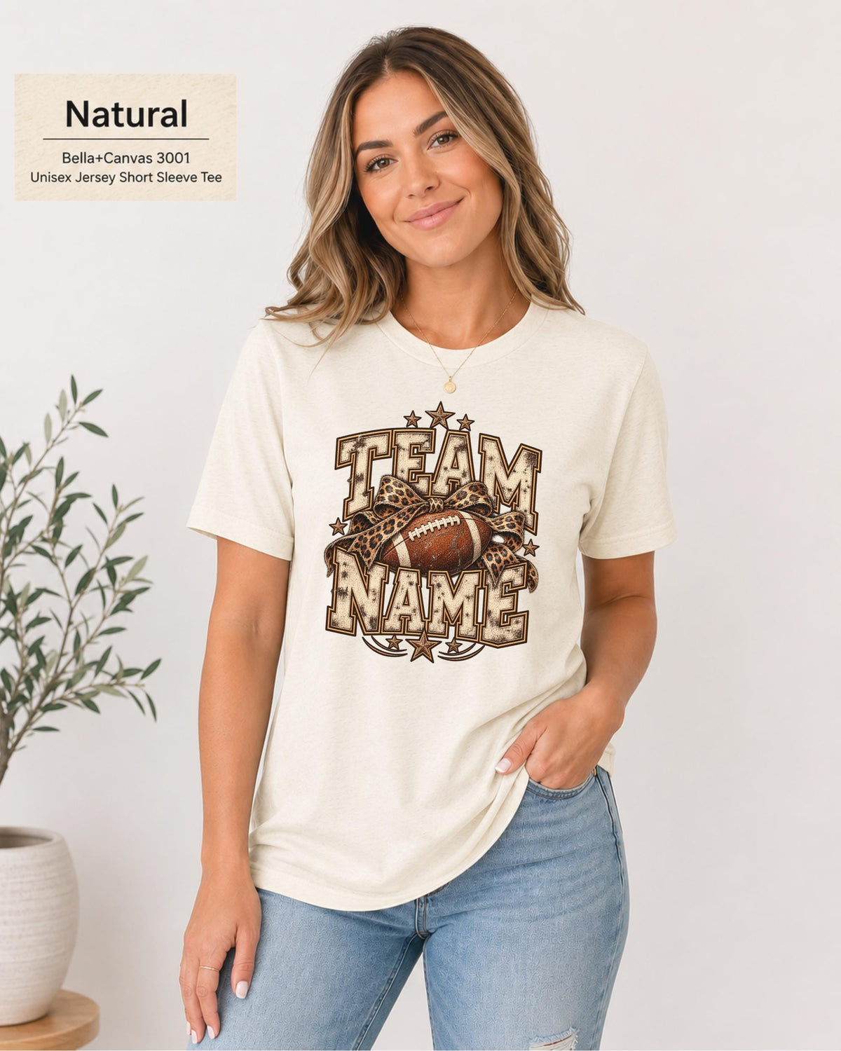 Natural Bella+Canvas 3001 unisex T-shirt featuring a customizable vintage football graphic with bold “Team Name” lettering, leopard-print bow, stars, and distressed varsity details.