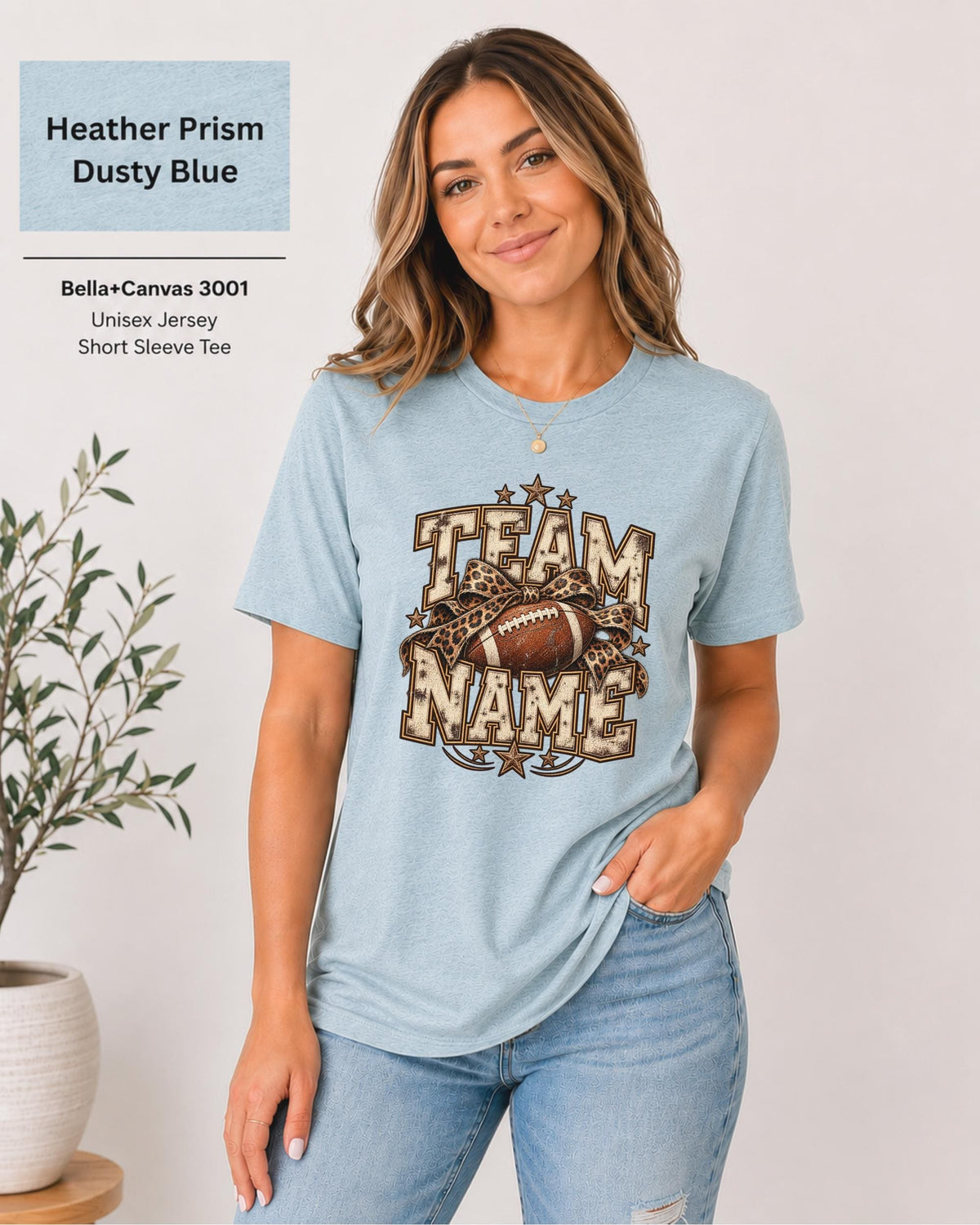 Heather Prism Dusty Blue Bella+Canvas 3001 unisex T-shirt featuring a customizable vintage football graphic with bold “Team Name” lettering, leopard-print bow, stars, and distressed varsity details.
