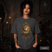 Female model wearing a graphite Comfort Colors 1717 shirt with a gold celestial Abundance design featuring sun and moon faces, crystals, stars, and moon phases.