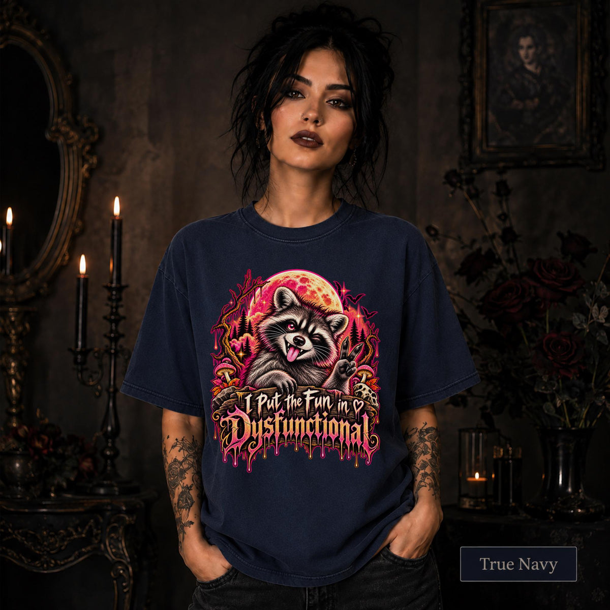 Female model wearing a true navy Comfort Colors 1717 tee featuring a colorful raccoon beneath a glowing moon with mushrooms and the phrase “I Put the Fun in Dysfunctional.”