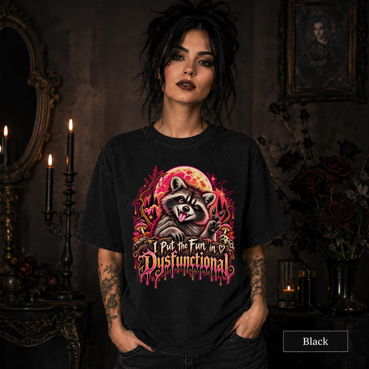 Female model wearing a black Comfort Colors 1717 tee featuring a colorful raccoon beneath a glowing moon with mushrooms and the phrase “I Put the Fun in Dysfunctional.”