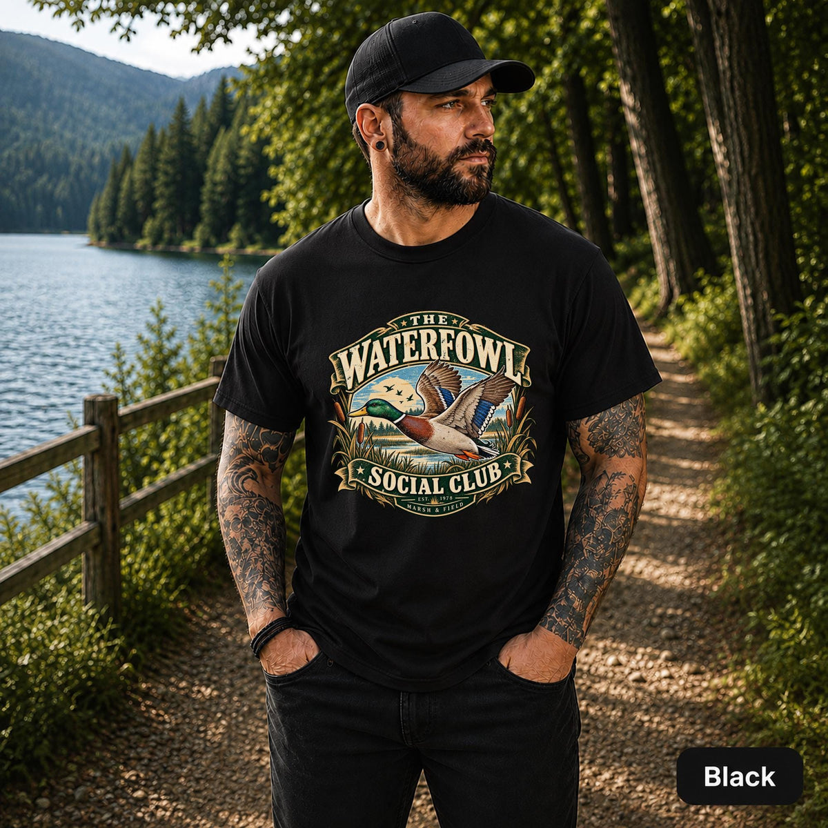 Black unisex T-shirt featuring the “Waterfowl Social Club” mallard duck graphic with marsh grass, lake scenery, and vintage outdoor styling.