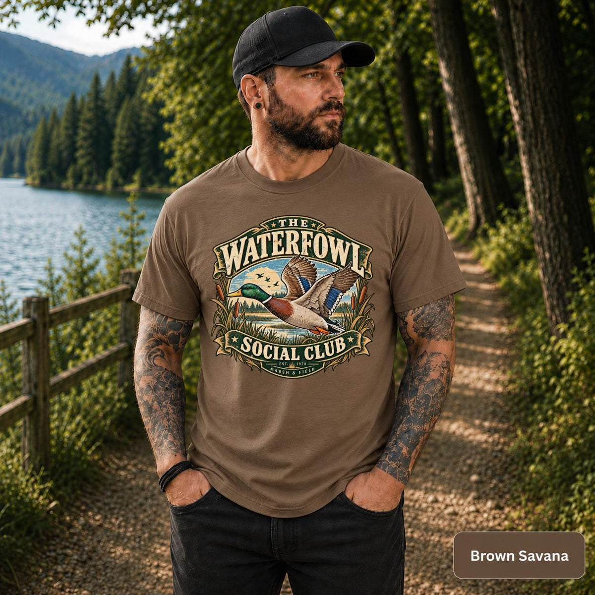 Brown Savana T-shirt showcasing the waterfowl graphic with flying mallard, marsh grass, and retro sporting club style.