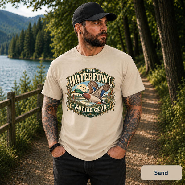 Sand tee featuring the “Waterfowl Social Club” design with lake scenery, reeds, and a vintage mallard illustration.