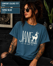 Topaz Blue Comfort Colors shirt showcasing the Jane Doe graphic with large lettering, deer artwork, and simple floral details.