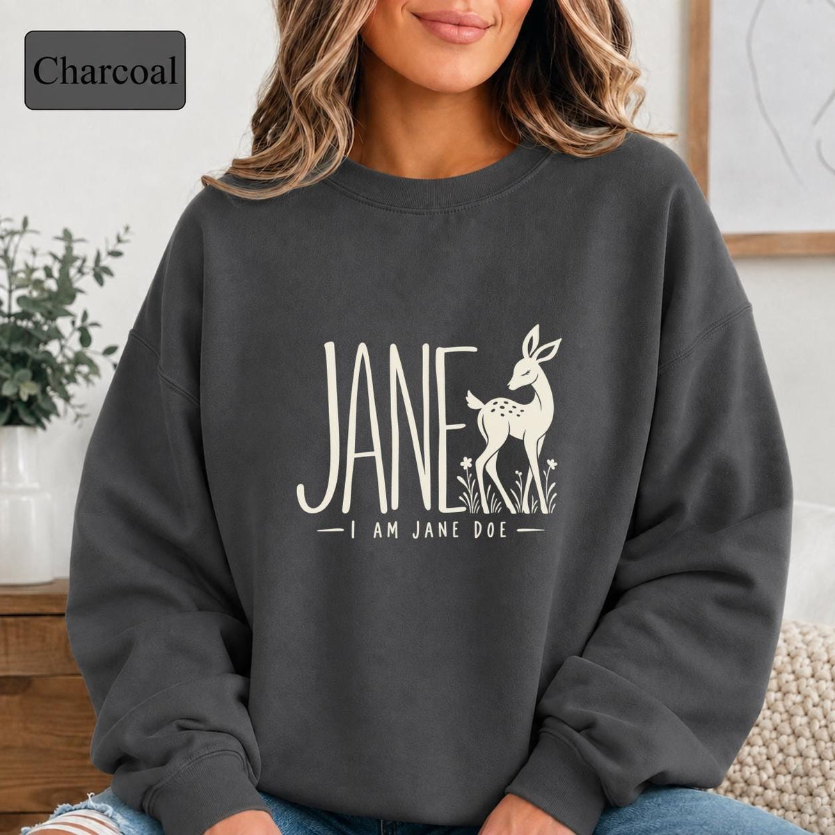 Charcoal sweatshirt displaying the Jane Doe solidarity design with neutral typography and a simple deer graphic.