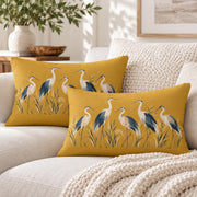 Two matching mustard yellow heron lumbar pillows styled together on a cream sofa with chunky knit blanket and neutral modern home decor.