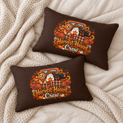 Two matching brown Harvest Haunt Crew lumbar pillows arranged on soft cream bedding with chunky knit blankets in a cozy autumn flat lay scene.