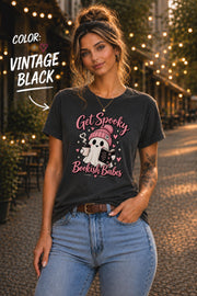 Get Spooky Bookish Babes T-shirt featuring a cute ghost in a pink beanie holding a book and coffee, with hearts and stars on a vintage black shirt.