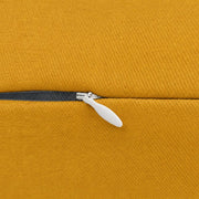 Close-up of mustard yellow pillow fabric showing the concealed zipper, dark zipper tape, and light metal zipper pull.