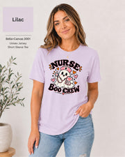 Nurse Boo Crew T-shirt in Lilac featuring a cute ghost nurse with a pink cap, stethoscope, clipboard, hearts, and playful Halloween accents.