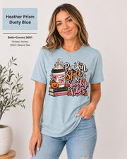 Bella+Canvas 3001 Heather Prism Dusty Blue unisex T-shirt featuring a “Pumpkin Spice & Spooky Vibes” design with a ghost reading, fall coffee, stacked books, jack-o’-lantern, hearts, and autumn leaves.