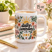 Daily Reminders ceramic mug 15 oz featuring colorful floral, sunshine, heart, and moon artwork with positive self-care phrases including drink water, be kind to yourself, you are enough, one step at a time, and progress over perfection.
