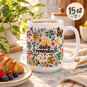 Daily Reminders ceramic mugs in 11 oz featuring colorful floral, sunshine, heart, and moon artwork with positive self-care phrases including drink water, be kind to yourself, you are enough, one step at a time, and progress over perfection.