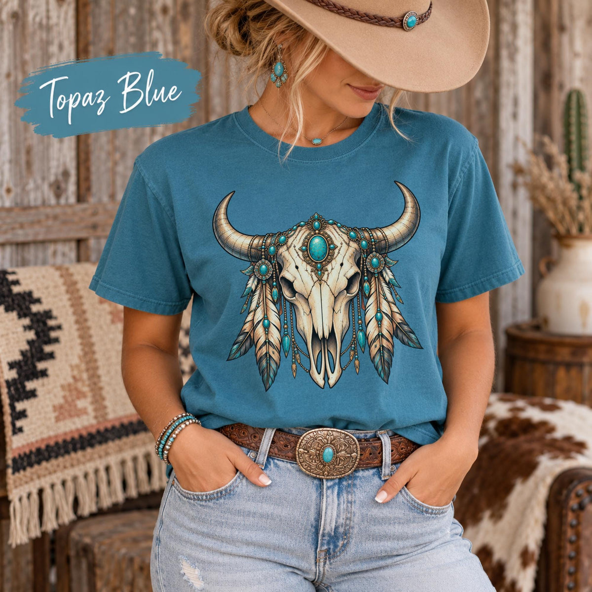 Topaz Blue tee displaying the boho longhorn skull graphic with teal stones, feather details, and rustic Southwestern styling.