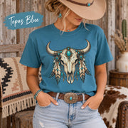 Topaz Blue tee displaying the boho longhorn skull graphic with teal stones, feather details, and rustic Southwestern styling.
