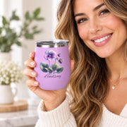 Lifestyle mockup showing a woman holding the personalized light purple birth month flower wine tumbler in a bright home setting.