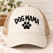 Natural women’s washed mesh-back cap featuring black embroidered “Dog Mama” lettering with a centered paw print.