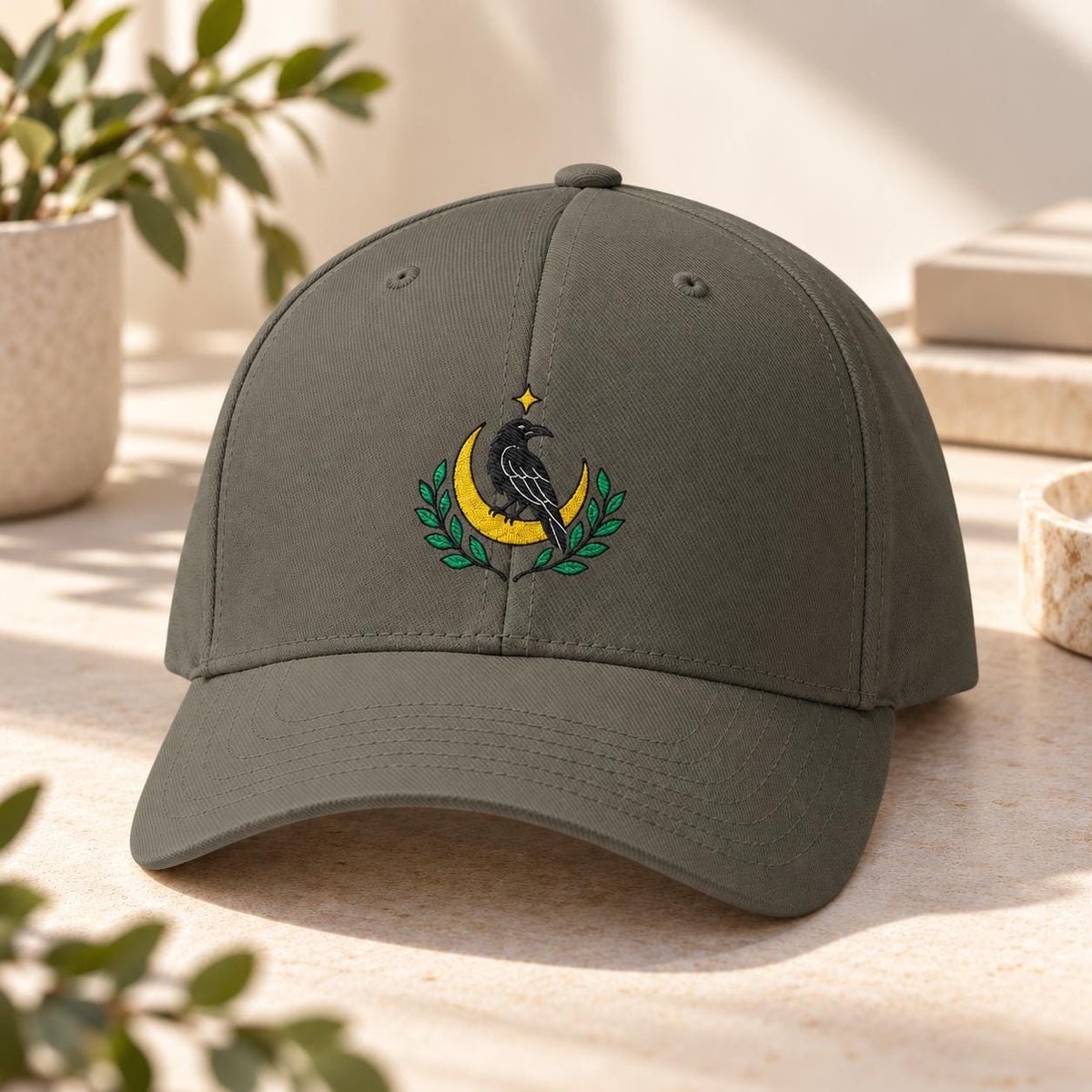 Dark olive structured cap featuring the raven moon artwork with green botanical accents and a curved bill.