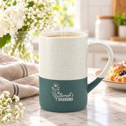 Forest Green and cream 13oz ceramic mug featuring a delicate engraved floral design with personalized “Grandma” wording, styled beside books and neutral home decor.