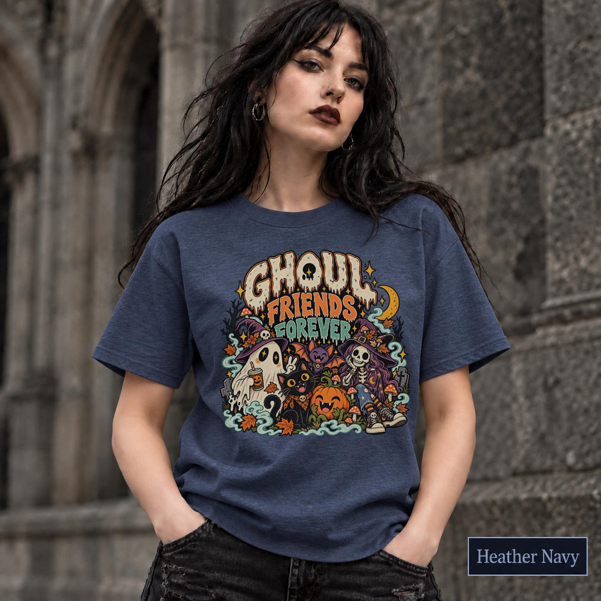 Heather Navy unisex T-shirt featuring a colorful “Ghoul Friends Forever” Halloween graphic with a ghost, black cat, pumpkin, witchy skeleton, bats, mushrooms, crescent moon, and autumn accents.