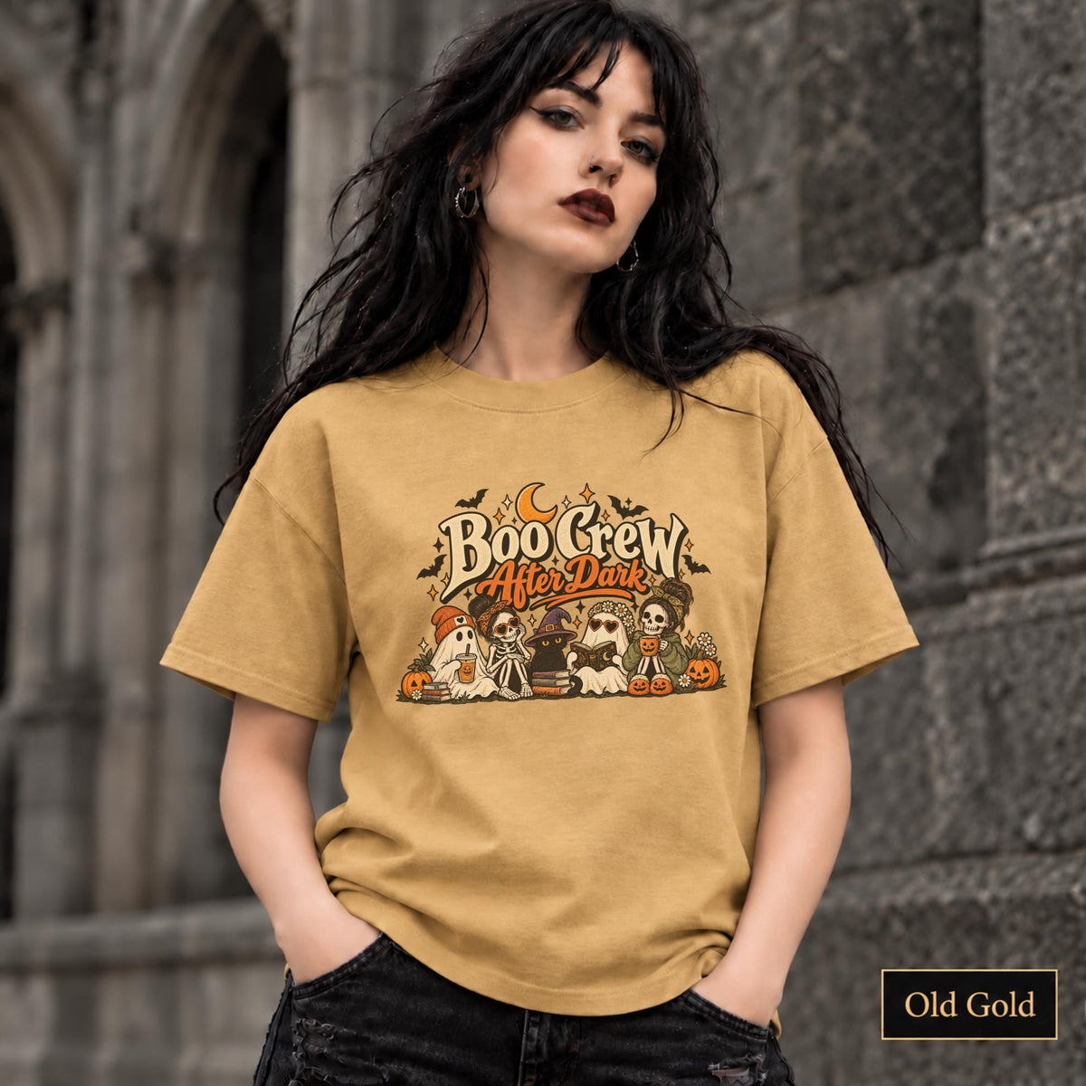 Old Gold unisex T-shirt featuring a “Boo Crew After Dark” Halloween design with ghosts, skeletons, pumpkins, books, bats, drinks, and a crescent moon in retro orange and cream tones.