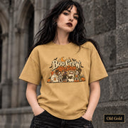 Old Gold unisex T-shirt featuring a “Boo Crew After Dark” Halloween design with ghosts, skeletons, pumpkins, books, bats, drinks, and a crescent moon in retro orange and cream tones.
