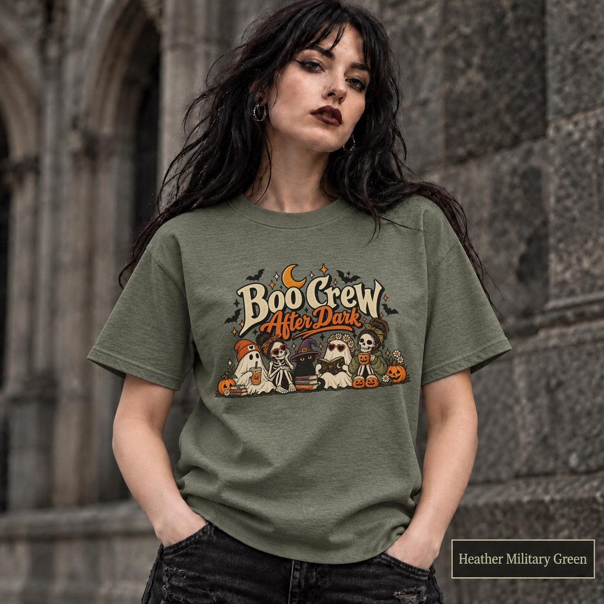 Heather Military Green unisex T-shirt featuring a “Boo Crew After Dark” Halloween design with ghosts, skeletons, pumpkins, books, bats, drinks, and a crescent moon in retro orange and cream tones.